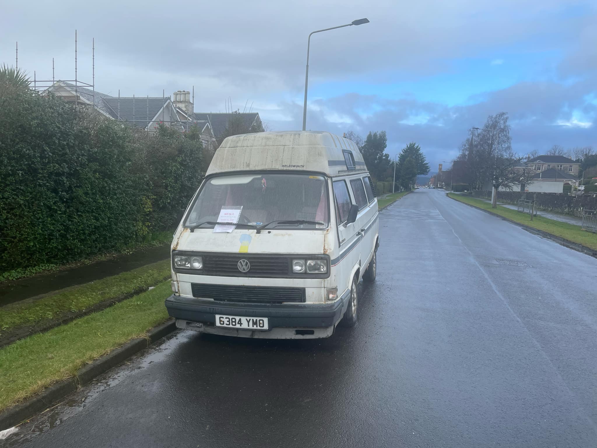 A white Volkswagen camper van parked by the side of the road